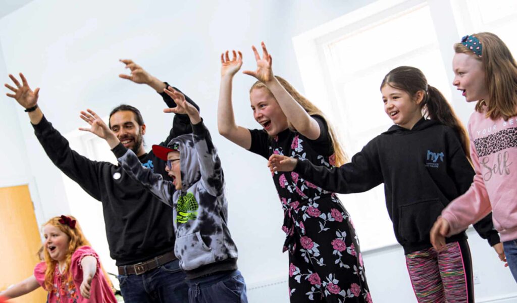 Group of children doing an acting exercise waving hands in the air