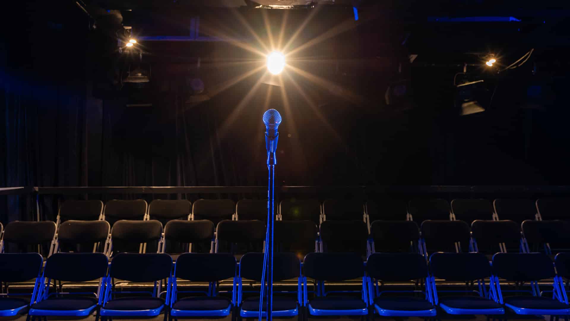 Microphone on stage with bright light and seats in front